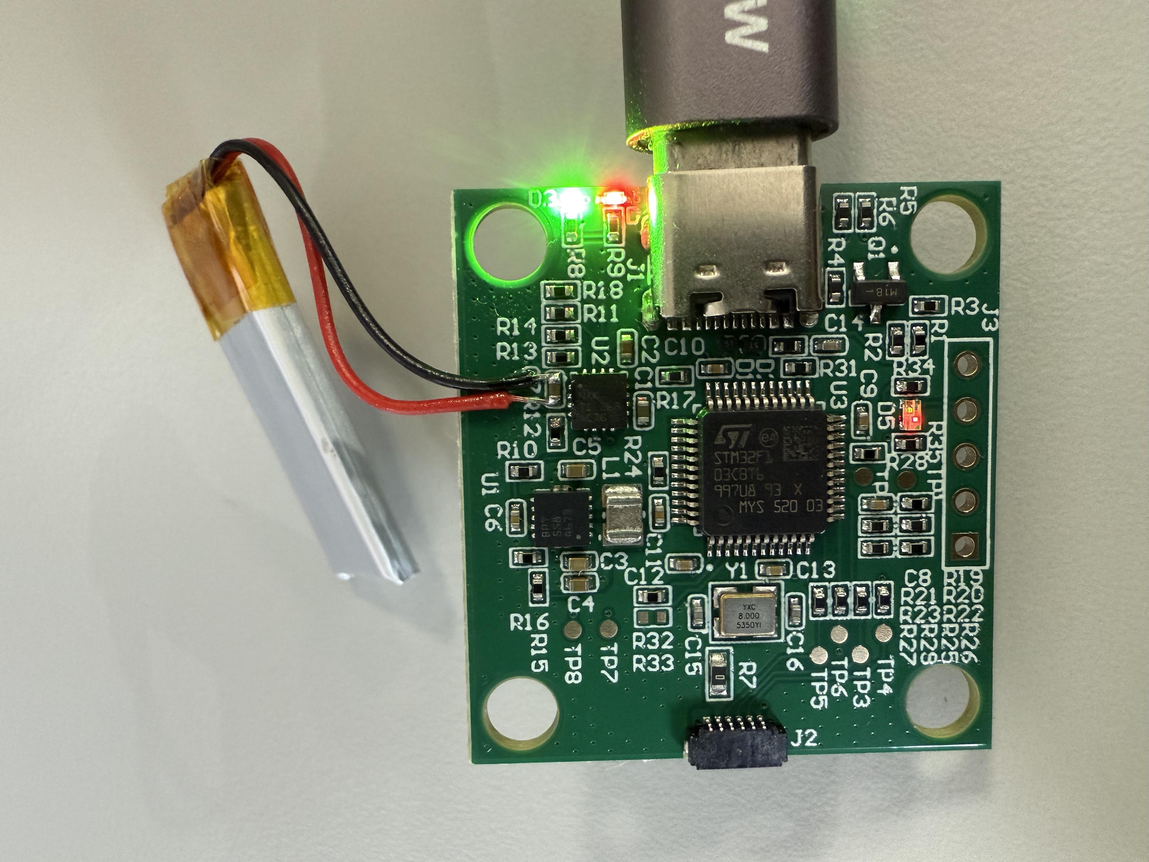 An original photograph of an UltraSense controller PCB with a battery, USB-C connection, illuminated LEDs, and surface-mount components.