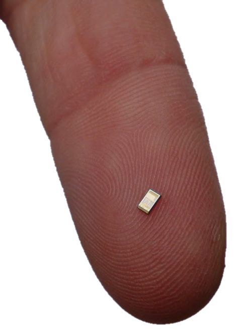 Extreme macro of a small surface-mount sensor chip resting on a fingertip.