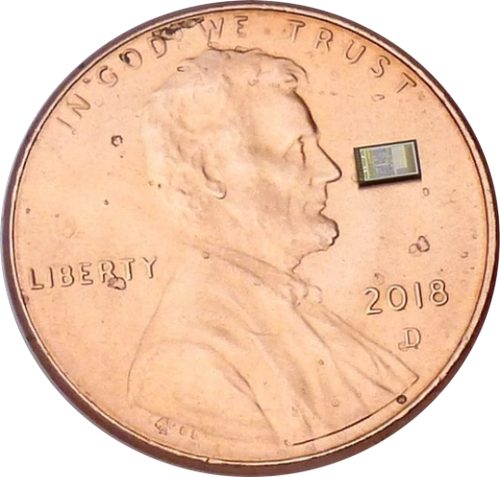 A touch-controller chip resting on a US penny, roughly a tenth of the coin's width.