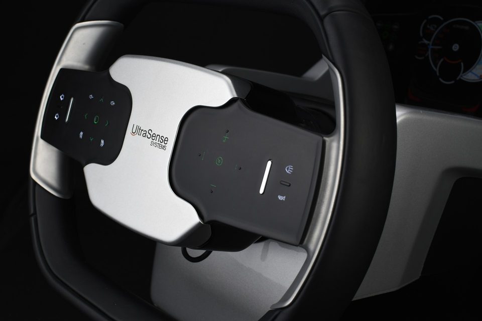 Metal touch panels integrated into a car steering wheel, with backlit green control icons lit through the surface.