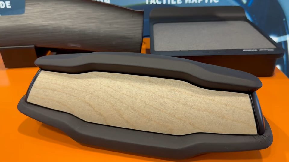 A shaped open-pore wood trim panel resting in its dark moulded housing on an orange surface.